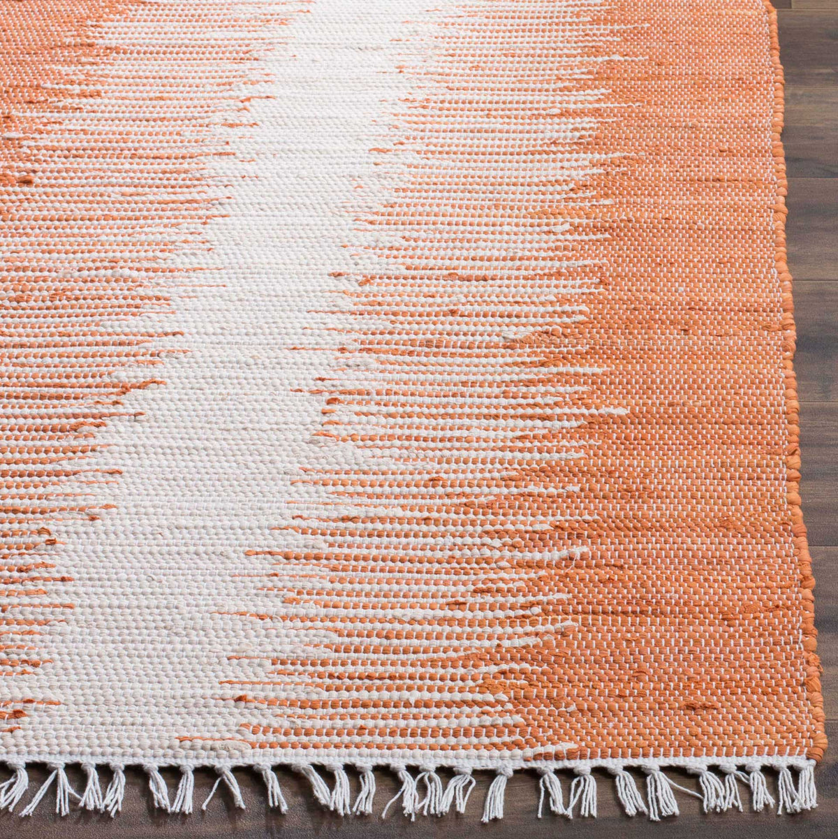 Orange and ivory woven stripes meet a neatly bound edge and loose cotton fringe.