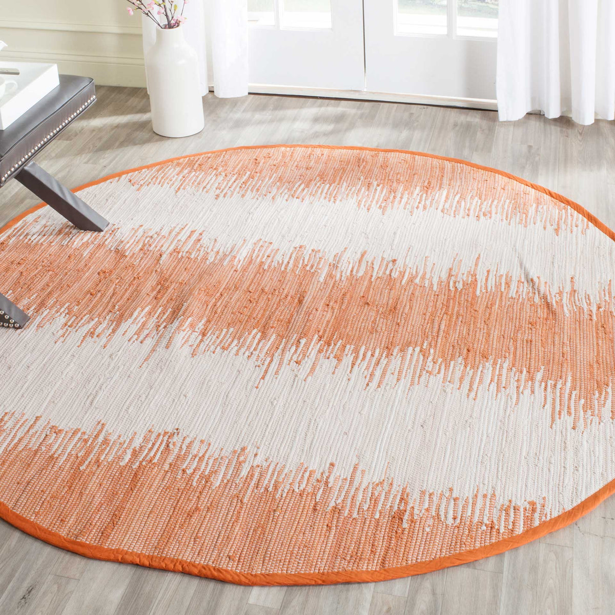 Bold orange and ivory stripes give this round cotton rug a warm, lively look