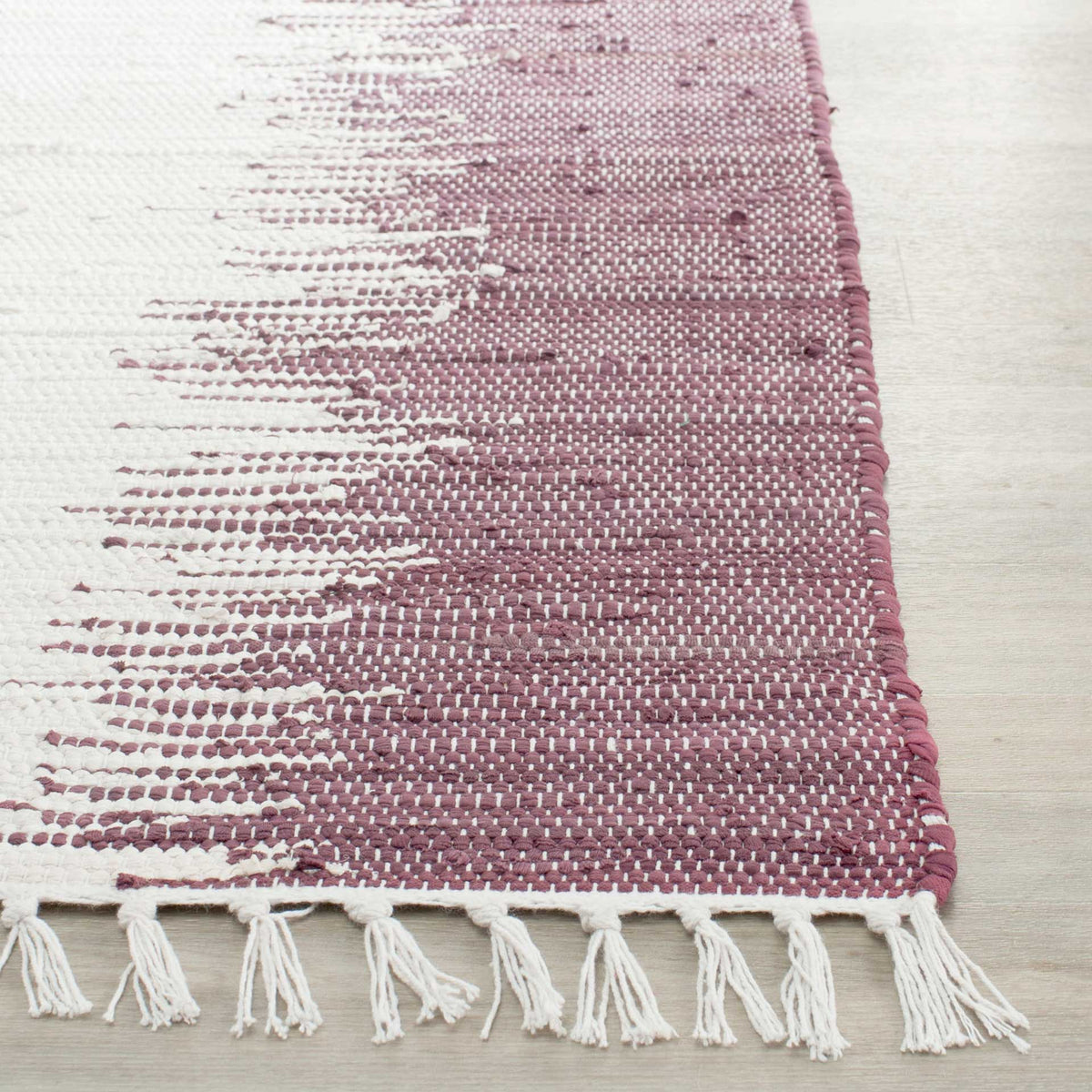 Purple and ivory cotton threads form a textured stripe beside a bound edge and knotted white fringe