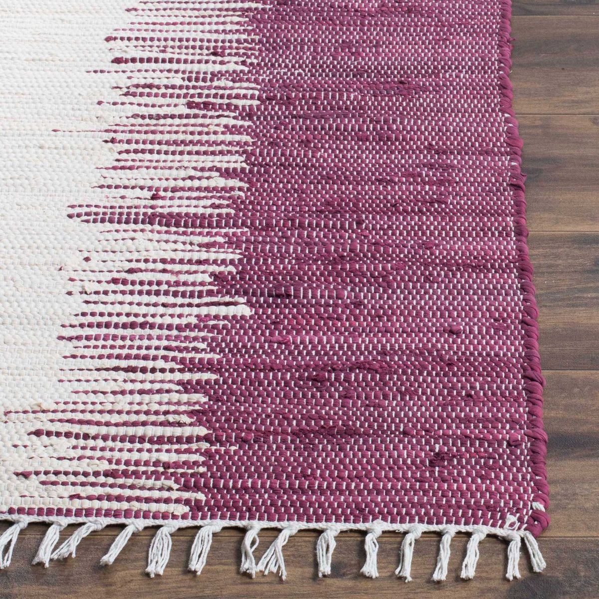 Plum and ivory yarns create textured stripes above a row of loose white cotton fringe.