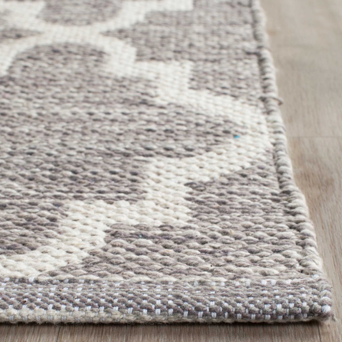 A neat woven border frames gray cotton texture and ivory quatrefoil curves.