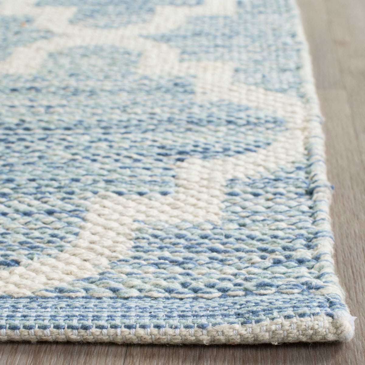 A neat blue and ivory woven border frames the rug's textured quatrefoil motif.