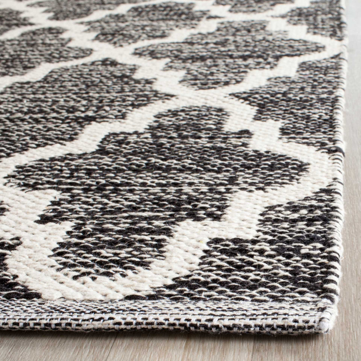 Black and ivory cotton threads create a tactile weave with a neatly bound corner.