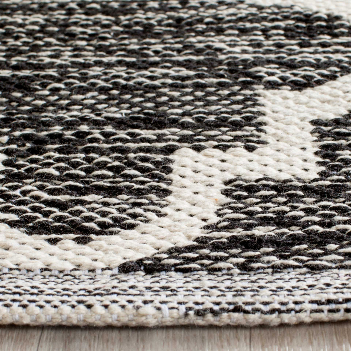 A tightly woven border complements the nubby black texture and bold ivory curves.