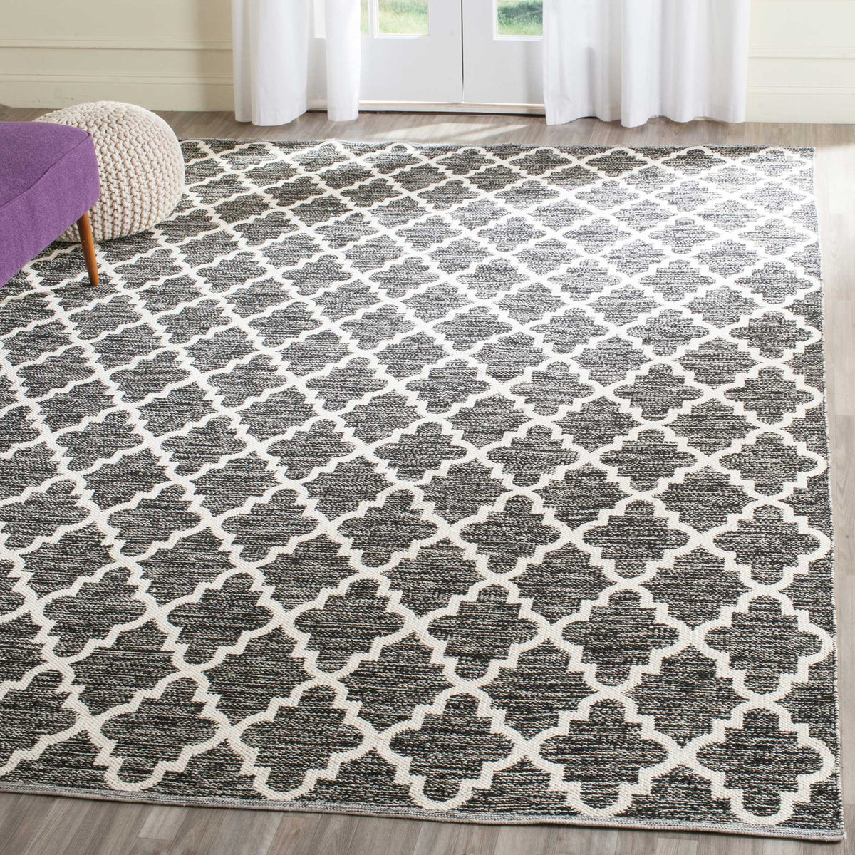 A black and ivory trellis rug anchors a bright living space with high-contrast style.