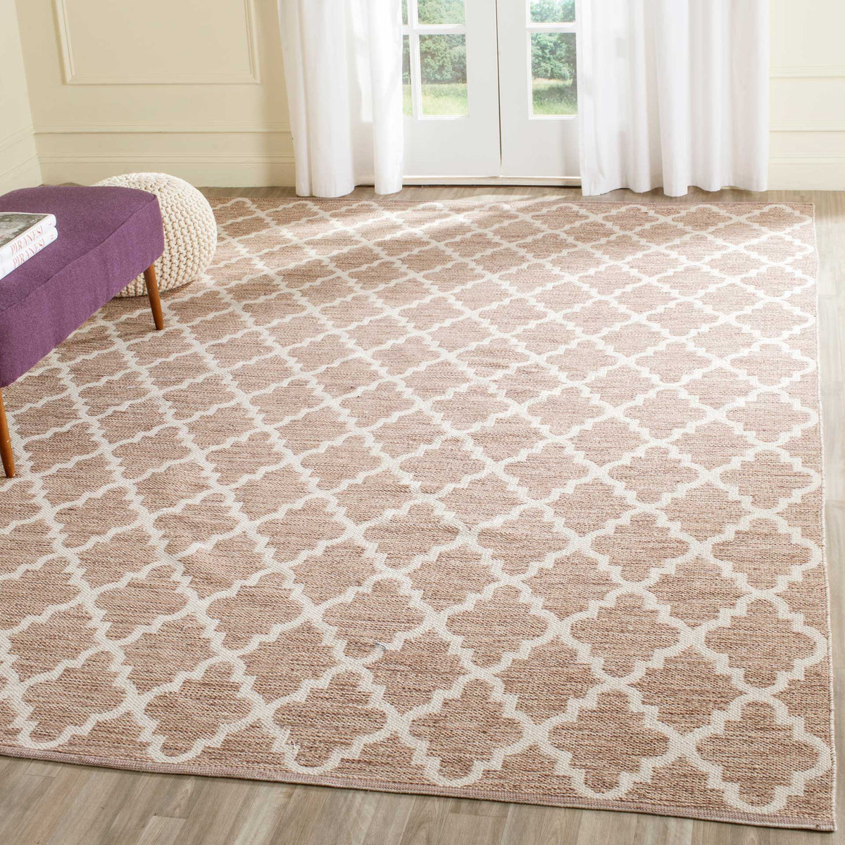 A generous beige and ivory trellis rug anchors a bright living space with woven warmth.