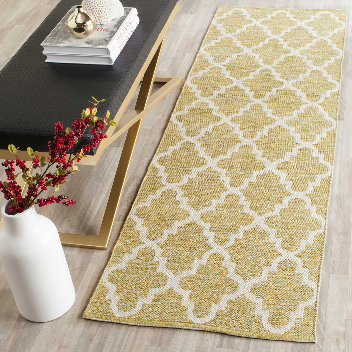 A golden olive and ivory trellis runner warms the wood floor beside a modern console.