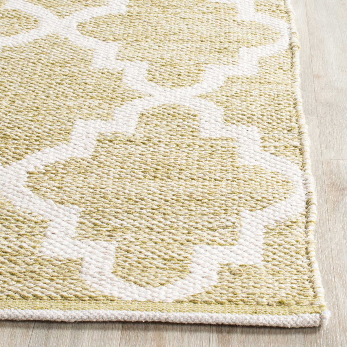 A tidy woven border finishes olive green cotton and the ivory quatrefoil design.