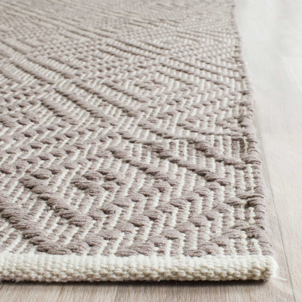 Raised gray cotton accents stand out against ivory lines and a neatly finished edge.