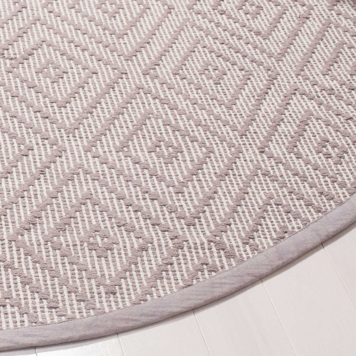 A bound edge frames the textured gray and ivory weave and repeating diamond motifs.