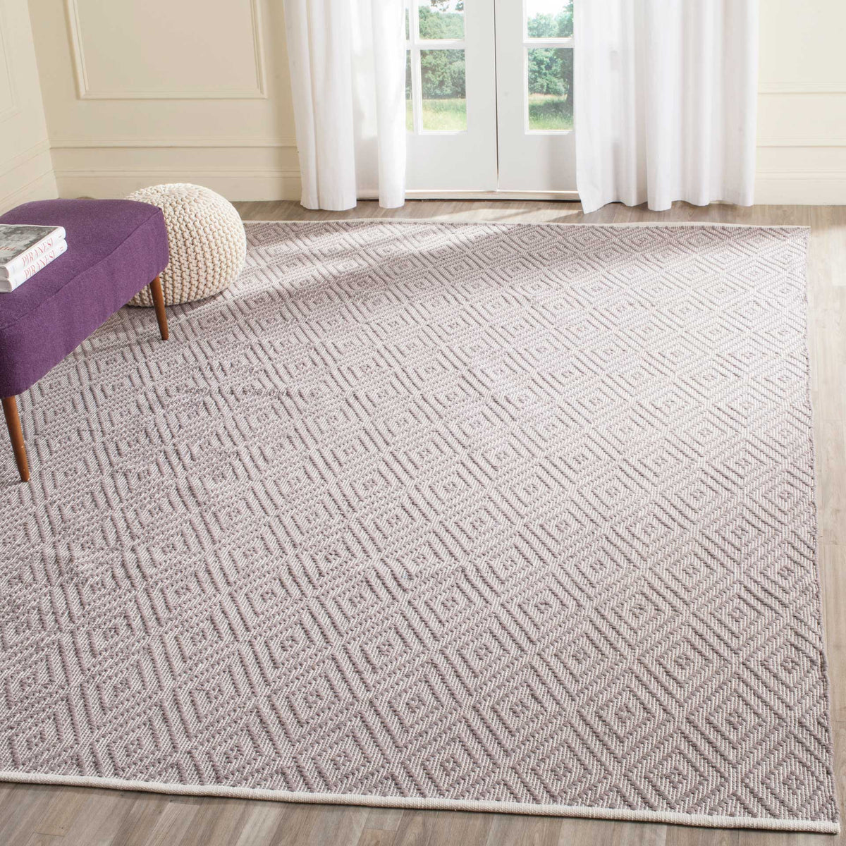 An expansive gray and ivory diamond rug layers gentle pattern over hardwood floors.