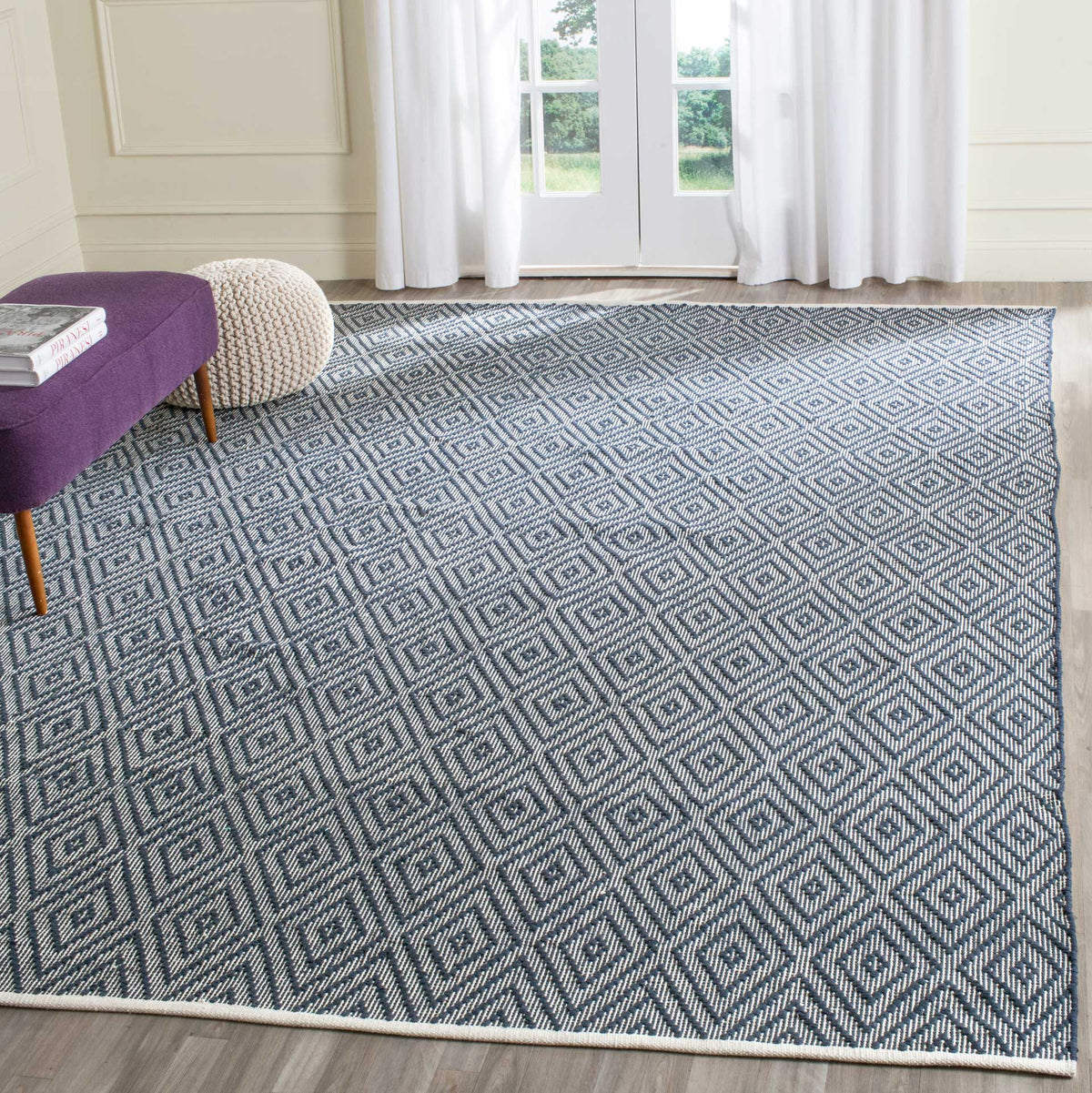 The generous navy and ivory diamond rug anchors a light-filled room with bold pattern.