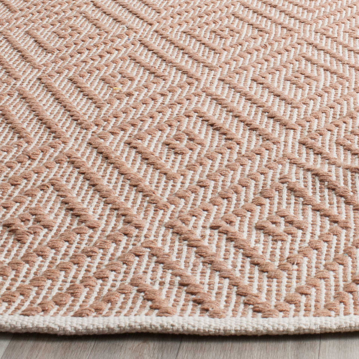 Raised beige diamond motifs stand out against ivory cotton beside a neatly bound edge.