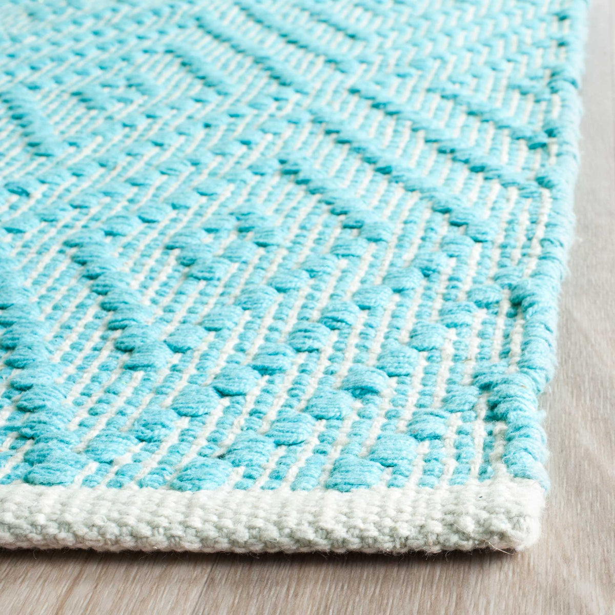 Vivid turquoise threads add texture against ivory, finished with a neatly woven edge.