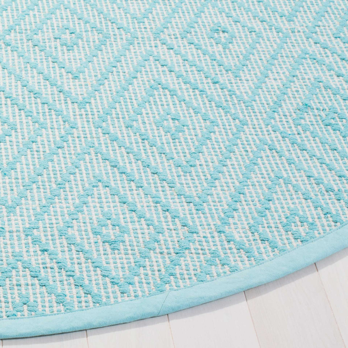 A turquoise bound edge frames the textured ivory and turquoise diamond weave.