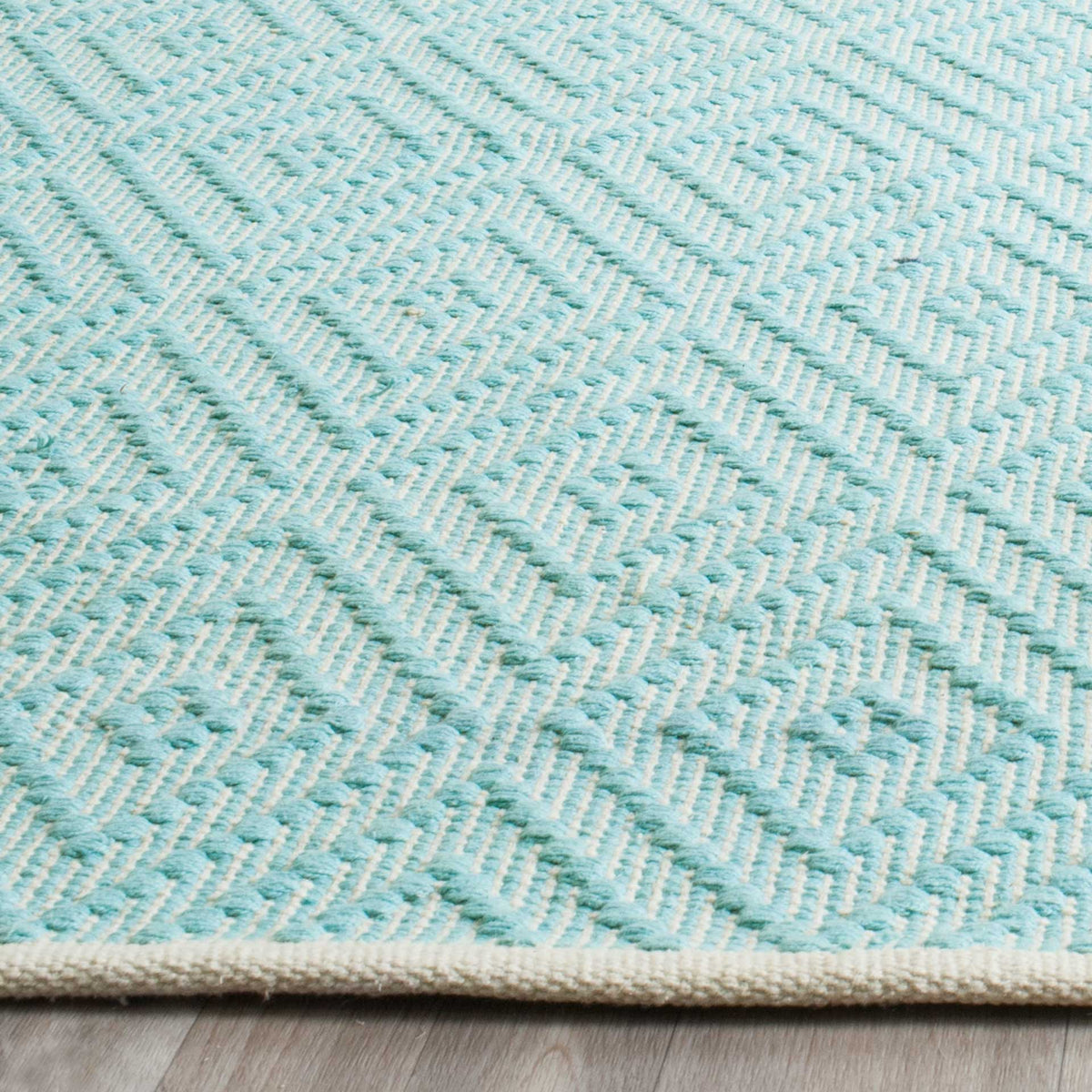 Turquoise woven diamonds and ivory loops create inviting texture above a bound edge.