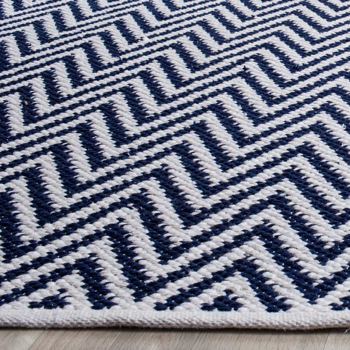 Raised navy and ivory zigzags bring rich texture to a neatly finished rug edge.