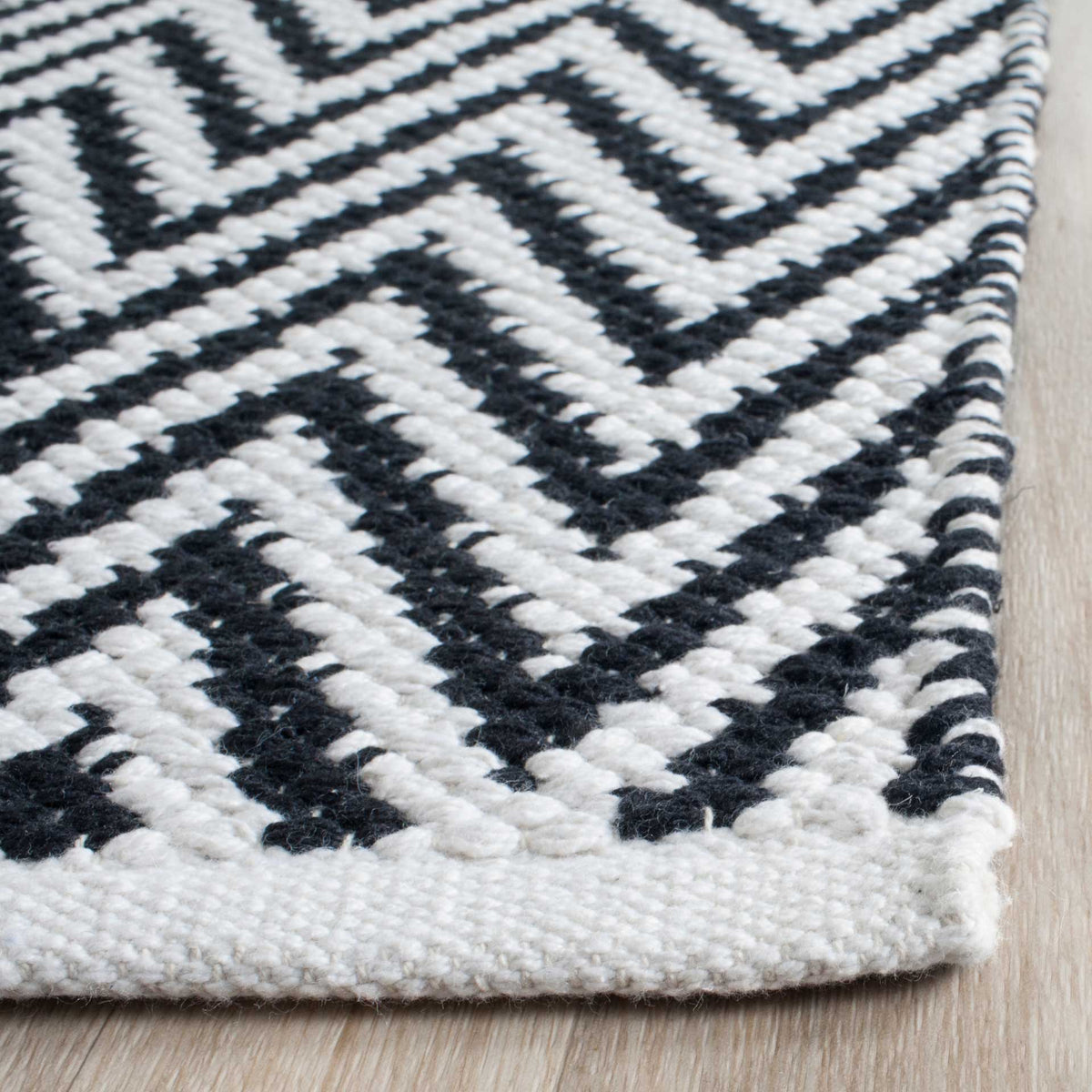 Textured black and ivory cotton stitches create crisp chevrons along a neatly woven edge.