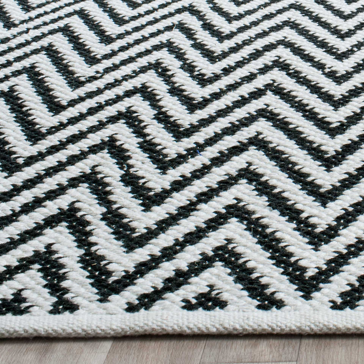Raised black and ivory cotton stitches trace dense chevrons above a woven edge.