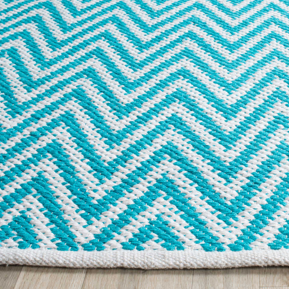 Alternating turquoise and ivory stitches form crisp zigzags above a woven border.
