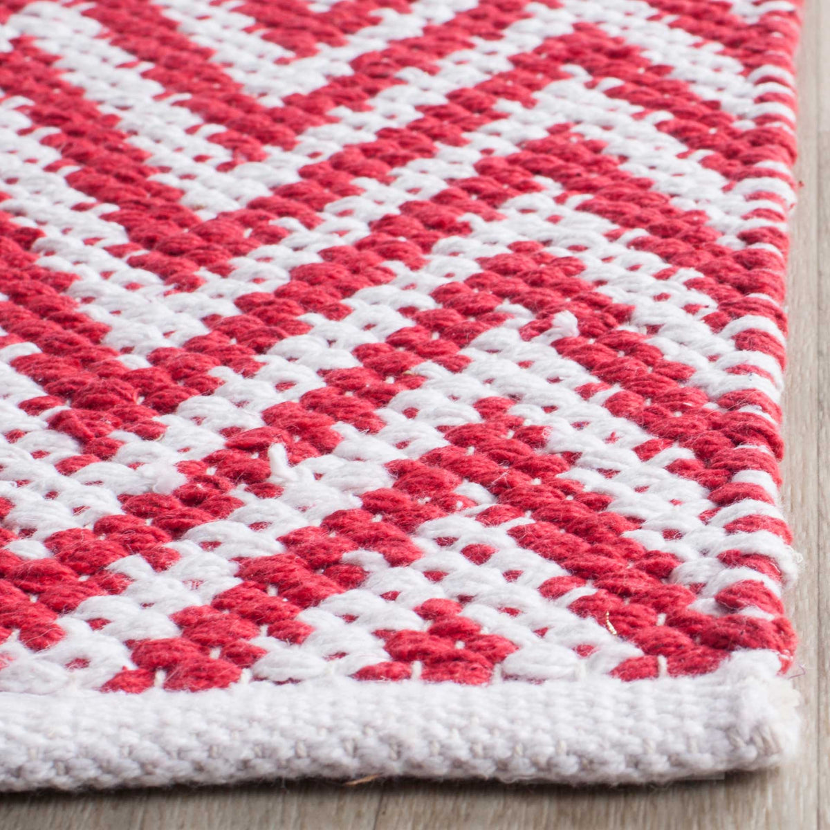 Plump red and ivory cotton yarns shape a textured corner with a finished edge.