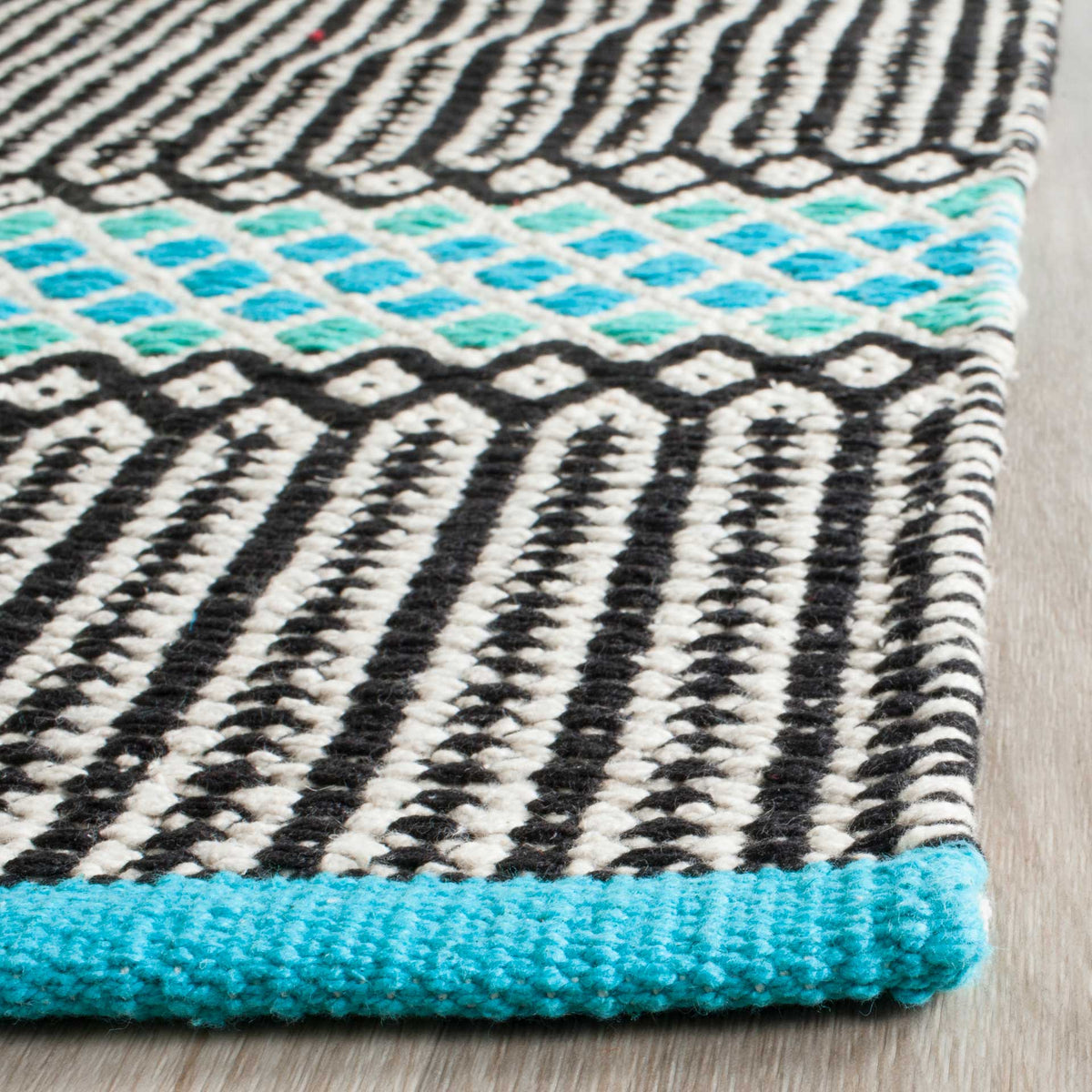 Textured black-and-white weaving meets a turquoise diamond band and a neatly bound edge.