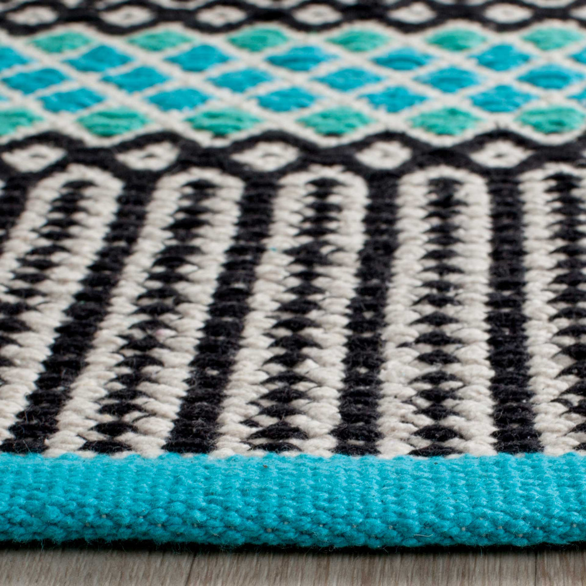 Turquoise edging finishes a woven corner with black stripes and colorful diamond motifs