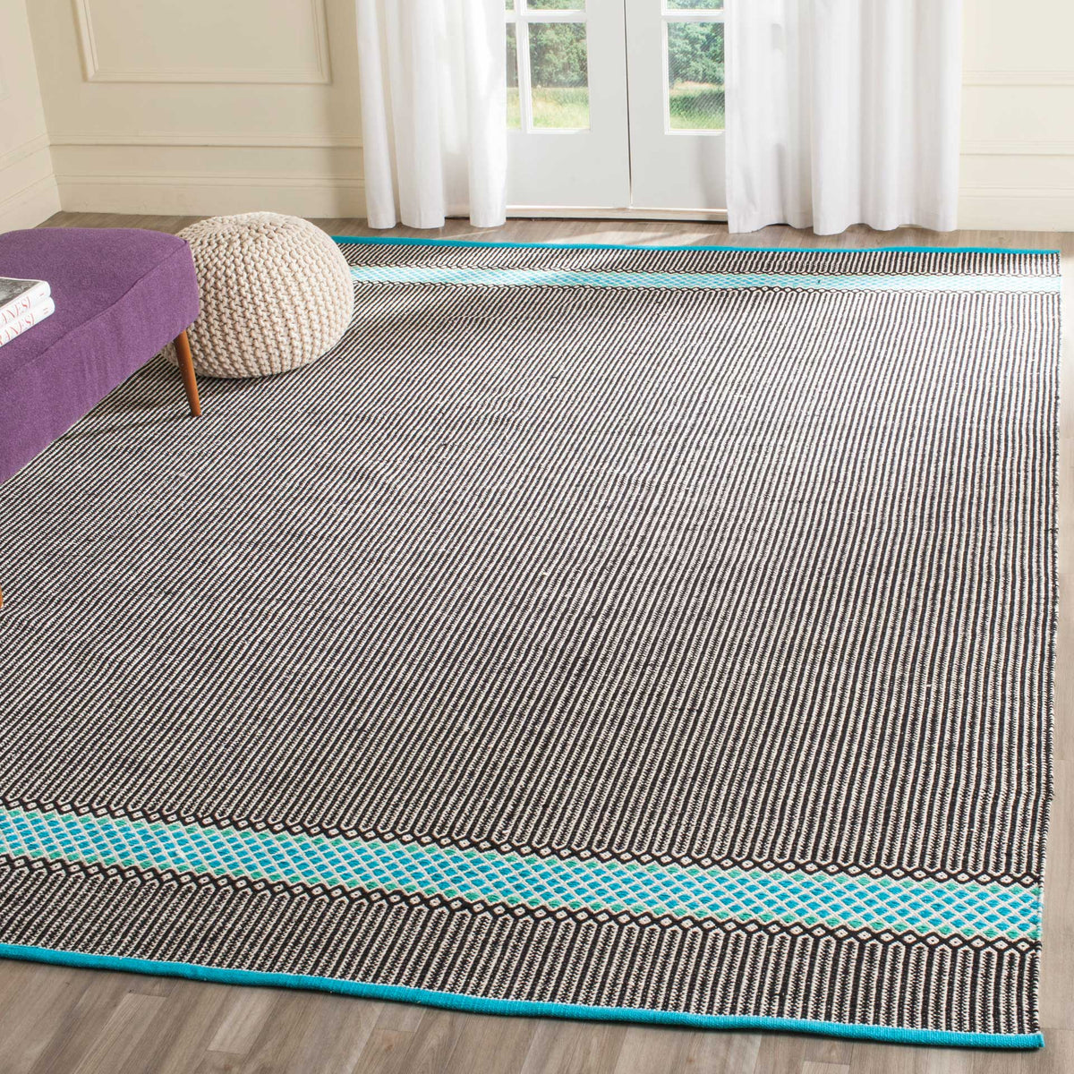 Turquoise border bands lend a bright accent to the rug's expansive black-and-cream striped field