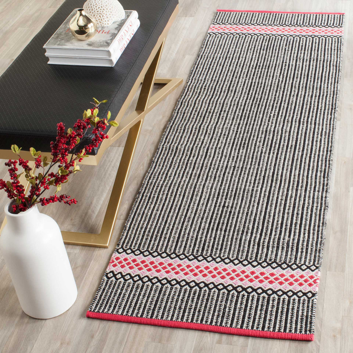 A slim striped runner with pink diamond borders adds color to a light wood floor.