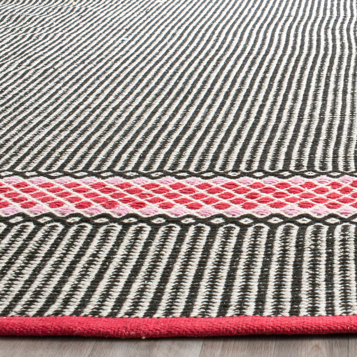 Close-knit black-and-cream stripes meet a pink diamond band and a neatly bound edge