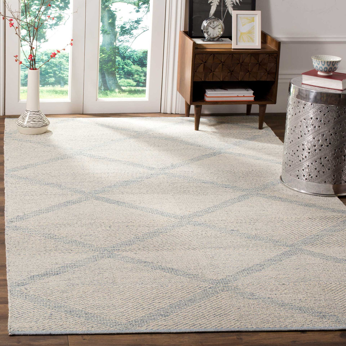 A pale blue diamond rug adds a calm, textured foundation to a sunlit living space.