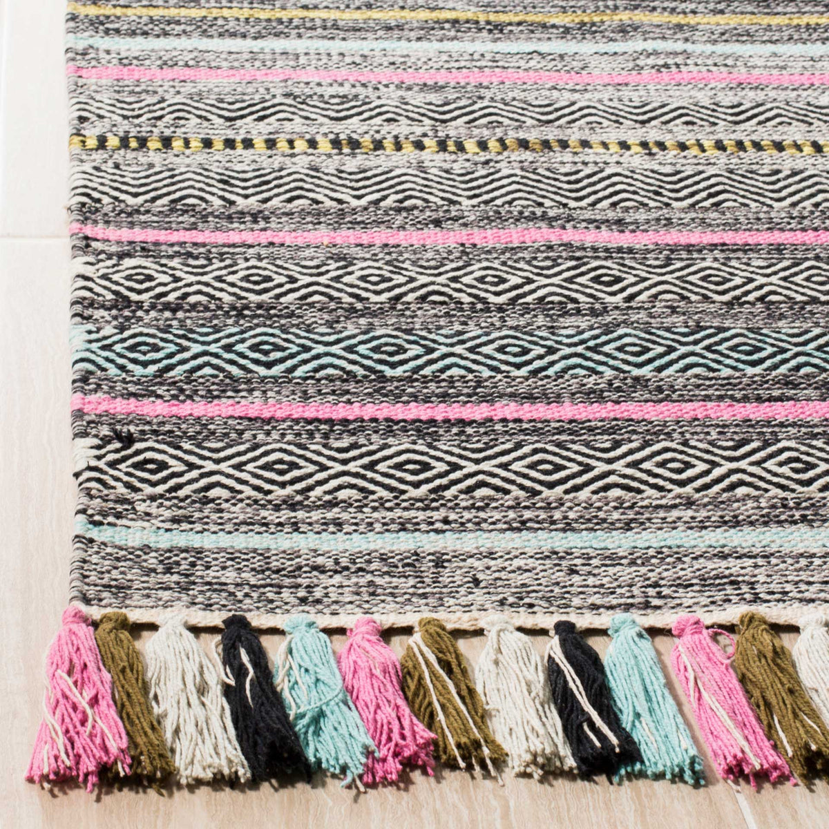 Bold black and ivory diamonds meet pink and aqua stripes above a row of colorful tassels.
