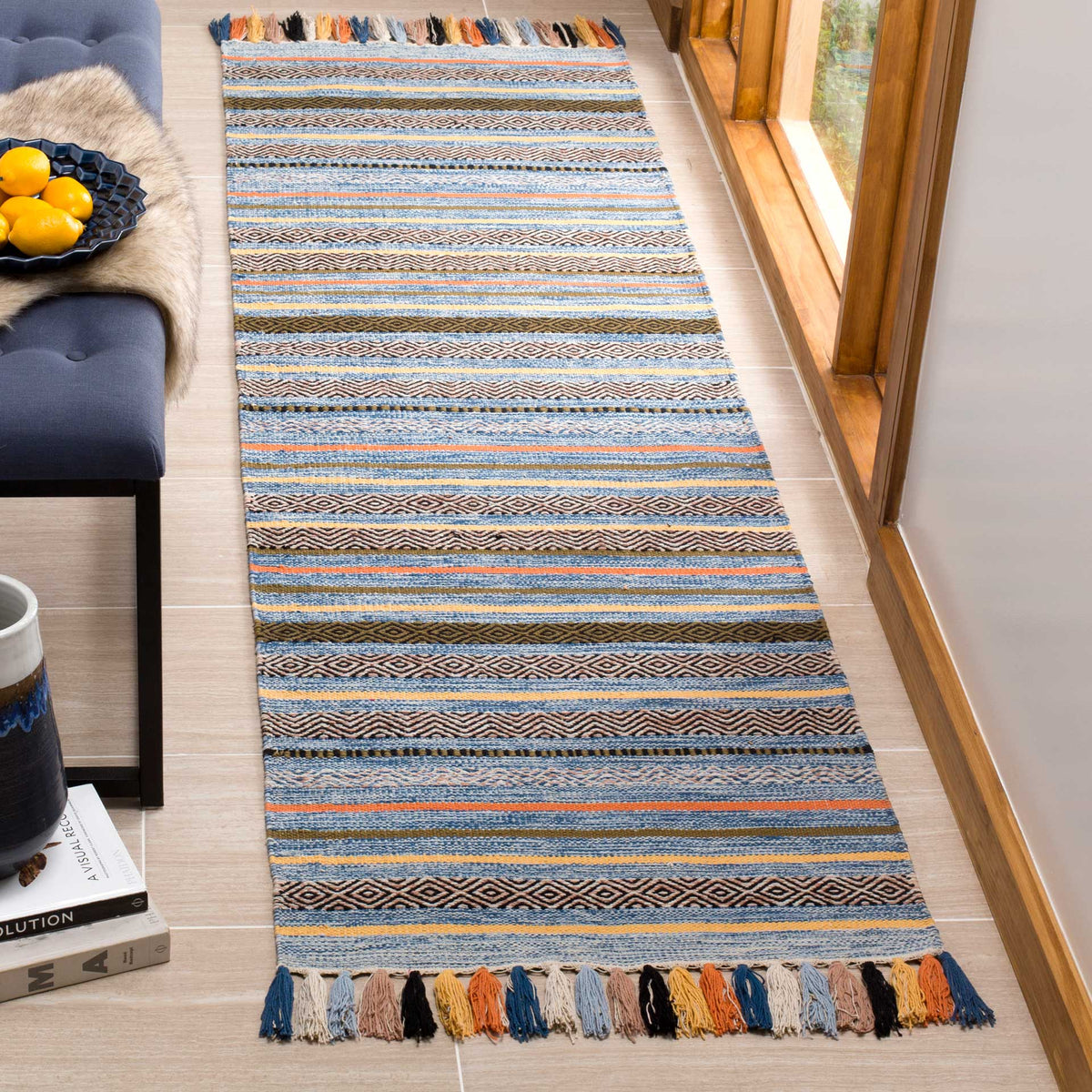 Narrow geometric bands and bright tassels add artisanal character to a blue runner