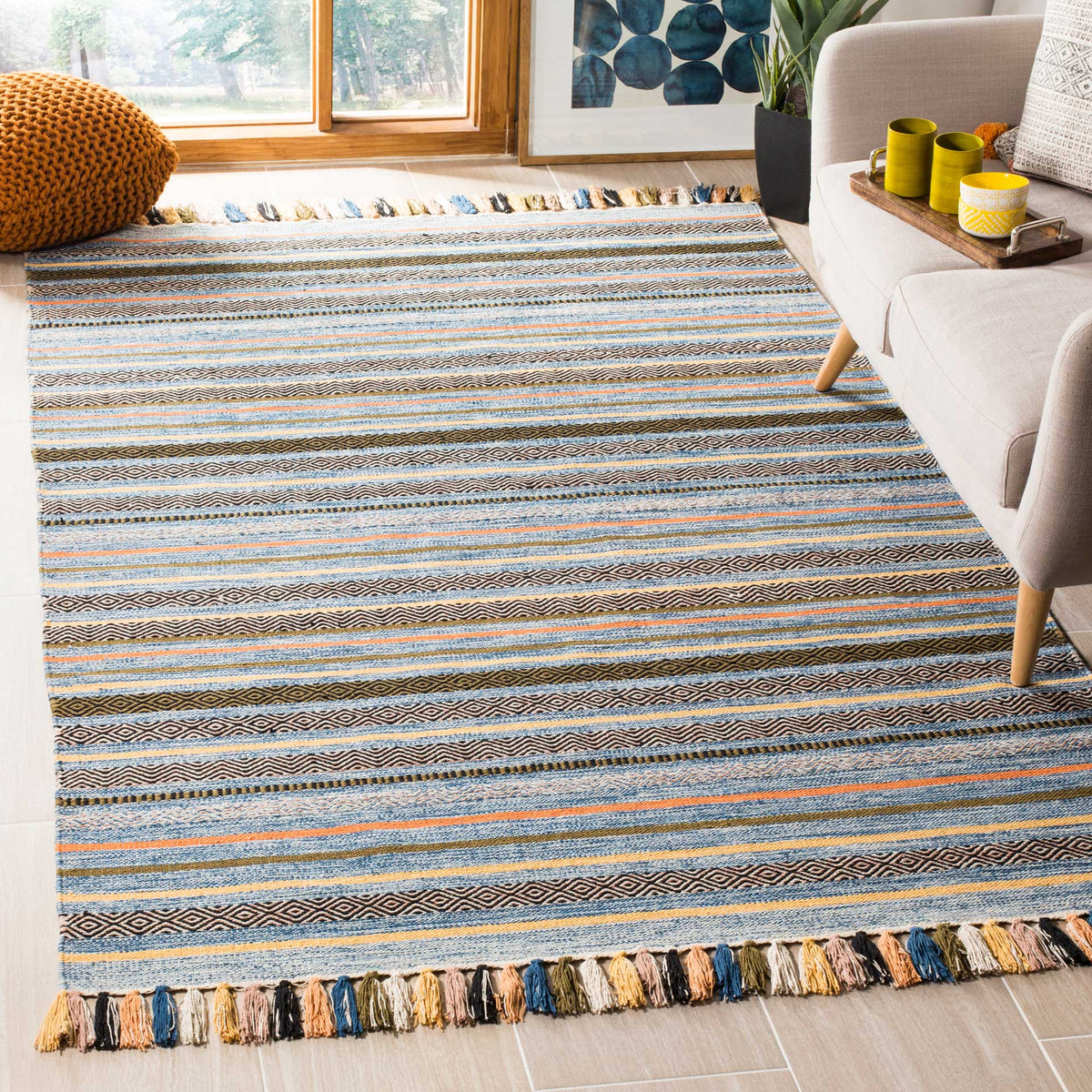 Blue patterned cotton rug accented with orange and cream stripes and vibrant fringed ends.