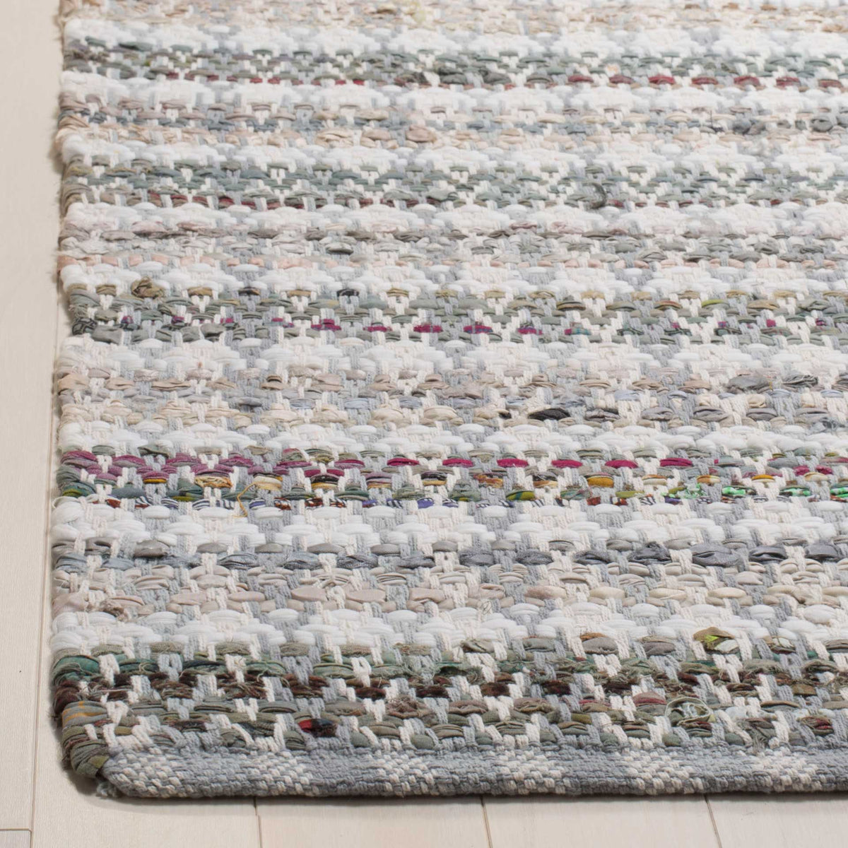 Textured gray and ivory cotton strands frame a neatly woven rug corner.