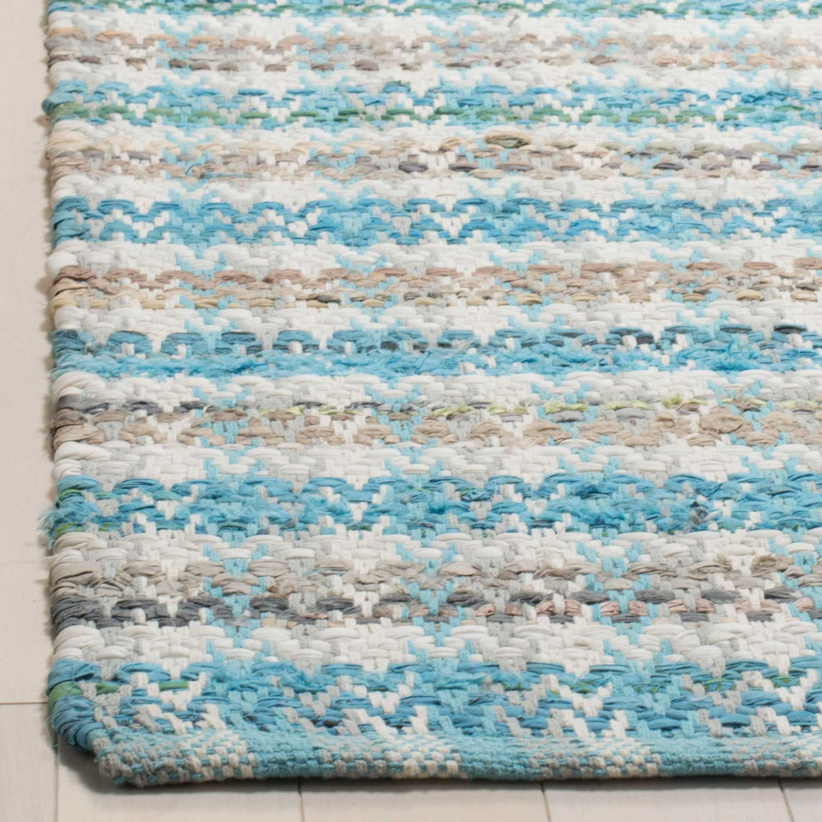Chunky aqua and cream cotton yarns meet at the rug's neatly finished corner.