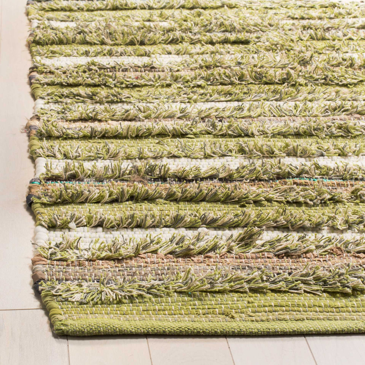 Nubby green and cream yarns form raised stripes above a neatly woven rug edge.