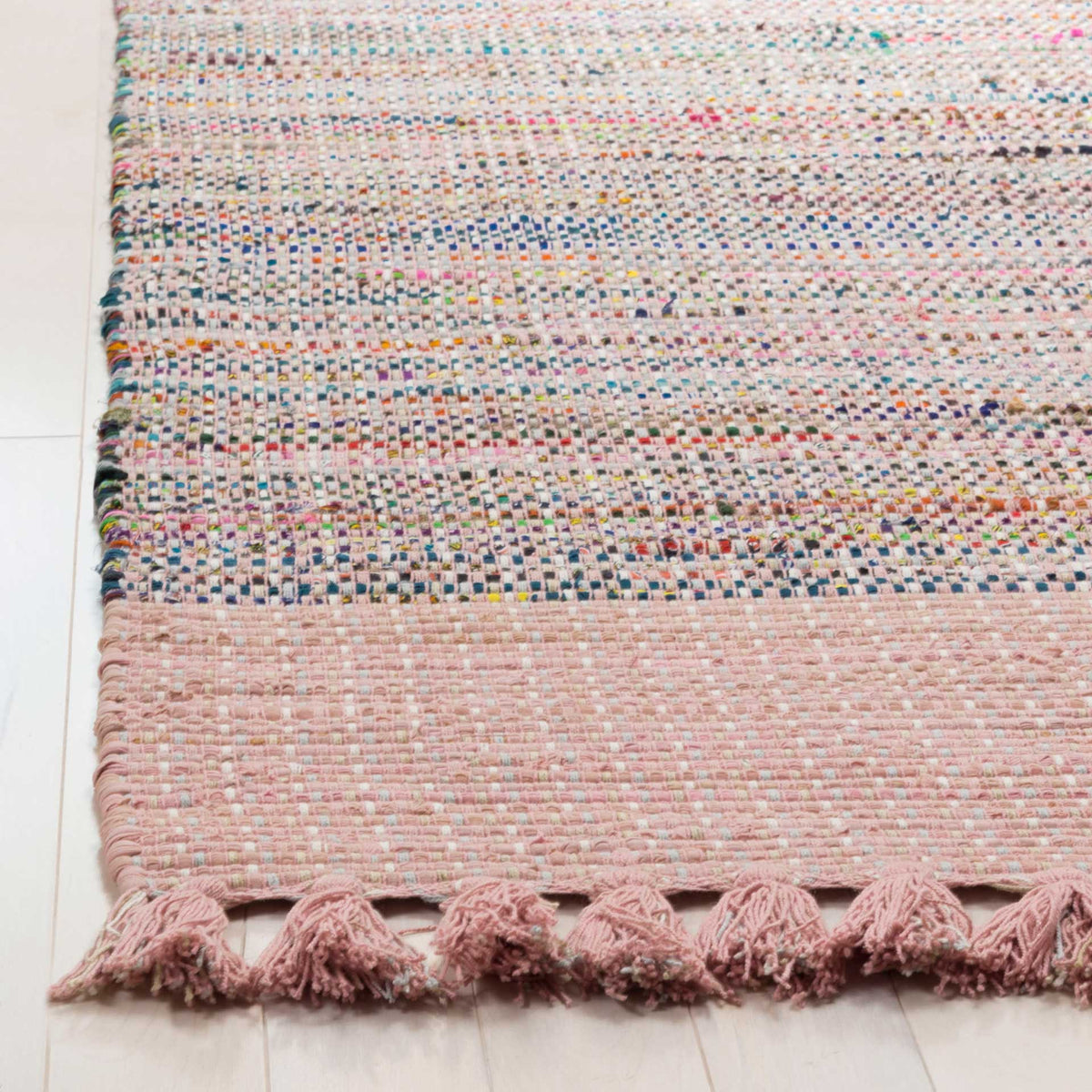 Blush pink woven border and tassel fringe set off the rug's colorful textured yarns