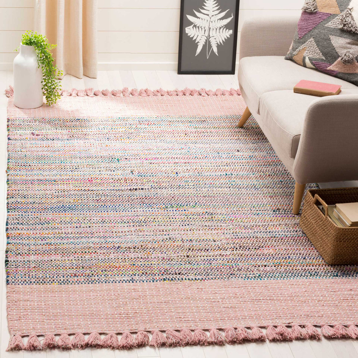 Pink cotton rug with colorful woven texture and tasseled ends warms a seating area