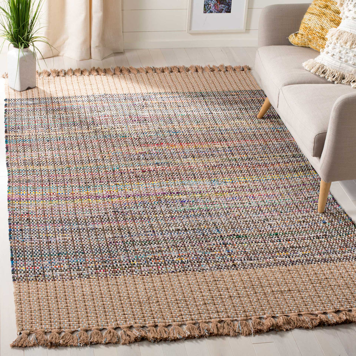 Beige cotton rug with flecks of bright color, wide woven borders, and tasseled ends
