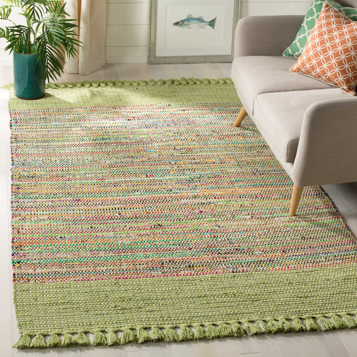 Green cotton rug layers multicolor woven stripes and tasseled edges beneath a sofa