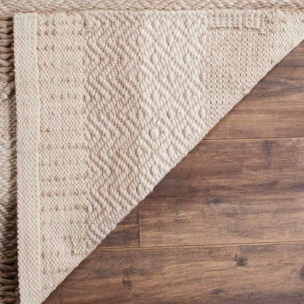 A folded corner reveals tightly woven backing beneath the rug's textured beige surface.