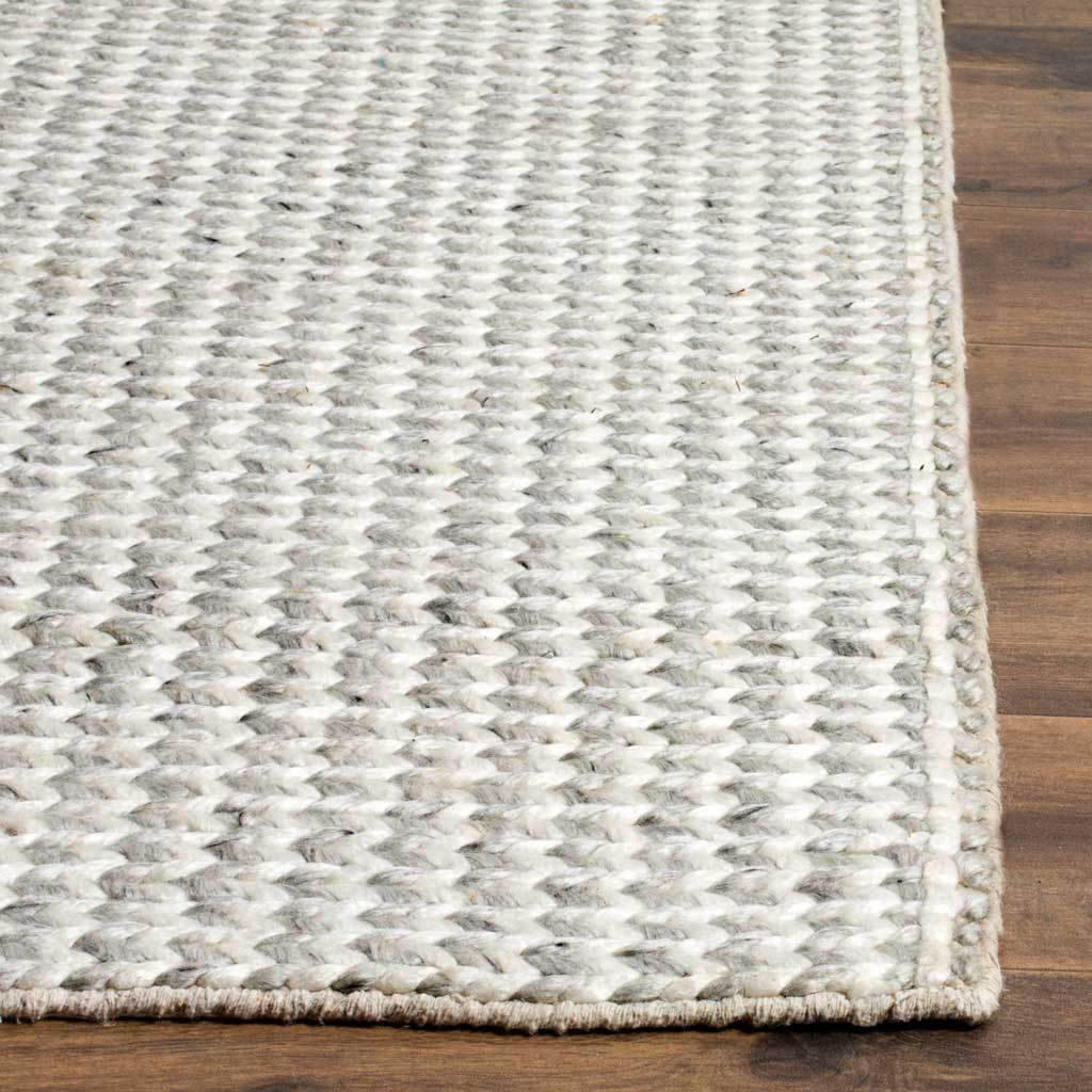 Thick ivory and silver fibers meet at a neatly bound corner for rich, tactile texture.