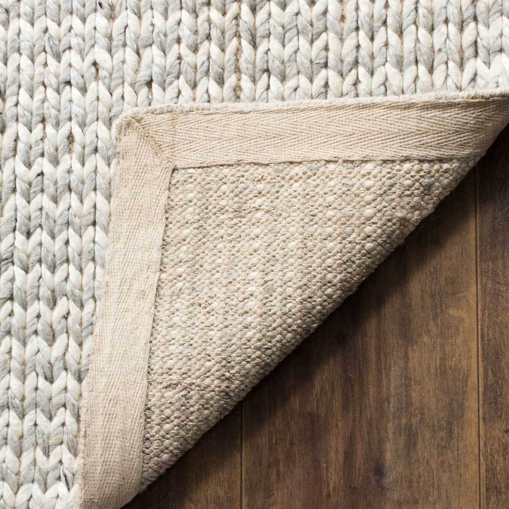 A folded corner reveals the rug's textured underside and sturdy fabric edging.