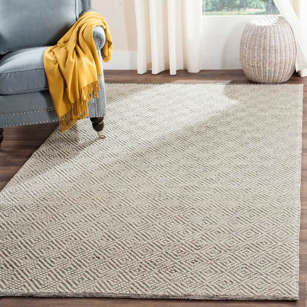 A softly textured ivory and light gray rug anchors the seating area with a fine diamond pattern.