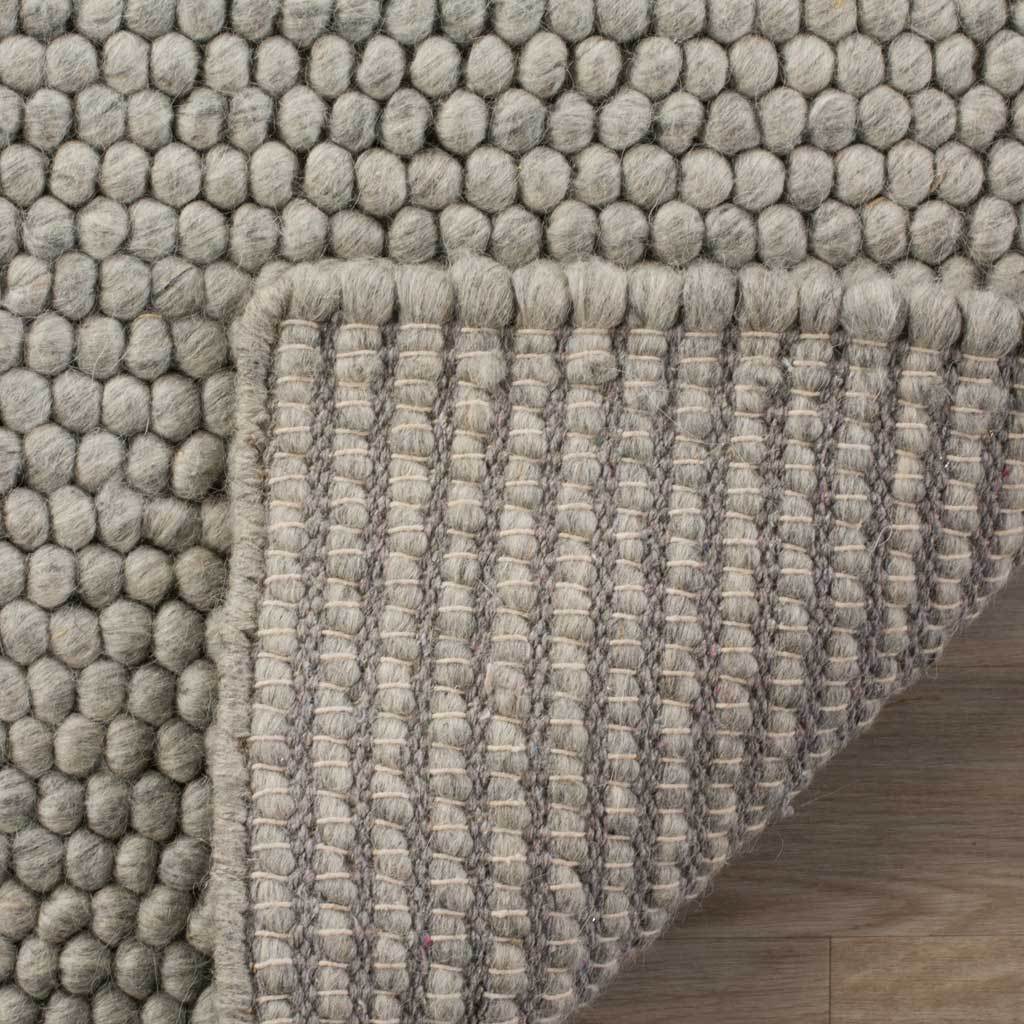 A tightly woven backing supports the silver-gray rug's rounded surface loops