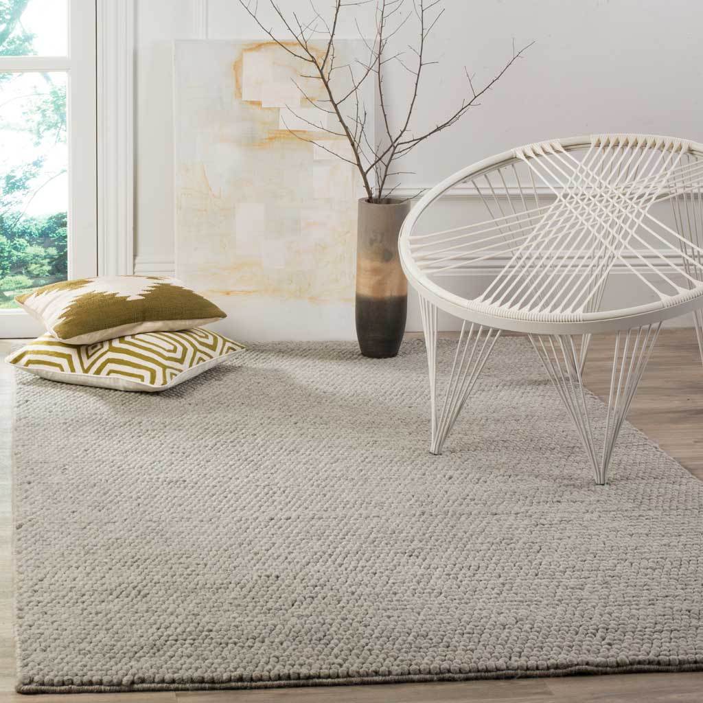 A silver-gray textured rug anchors a bright seating area with understated softness