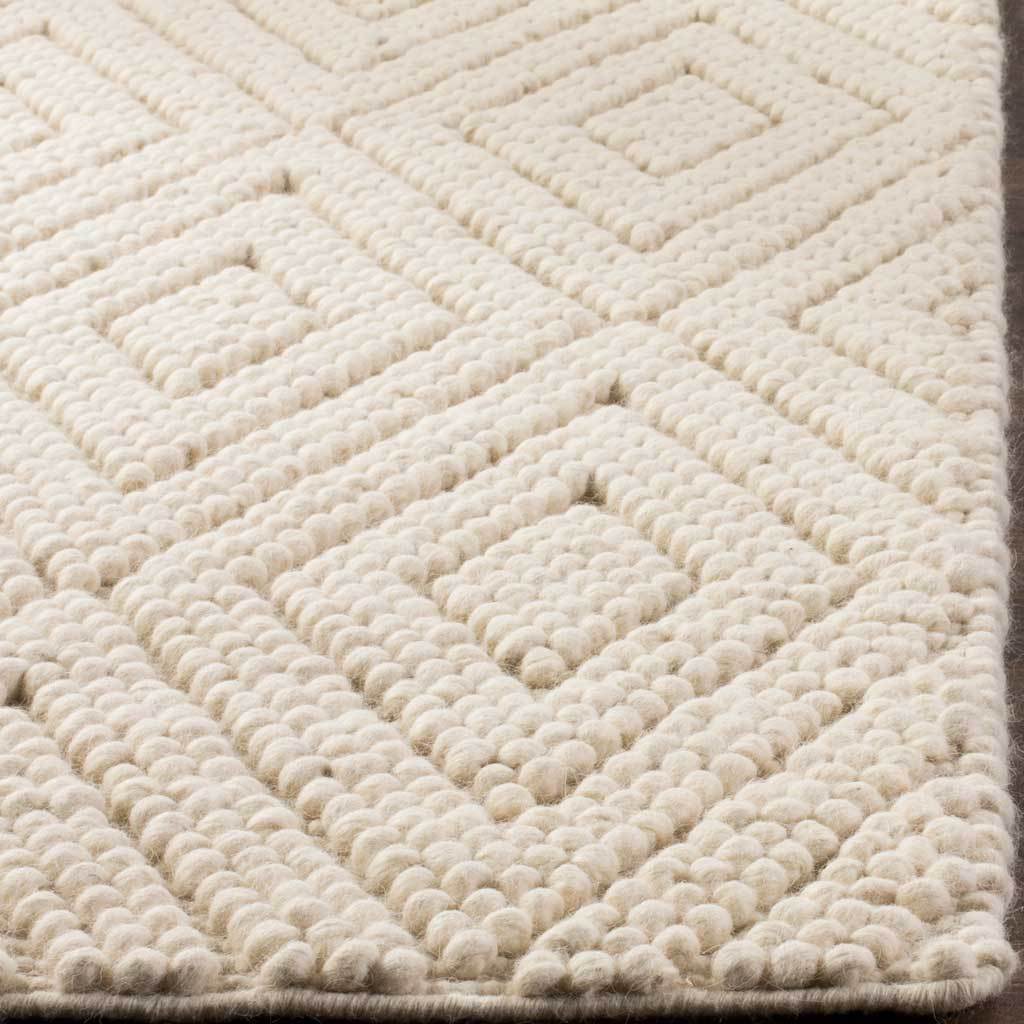 Rounded ivory wool loops form raised nested diamonds beside a neatly finished rug edge