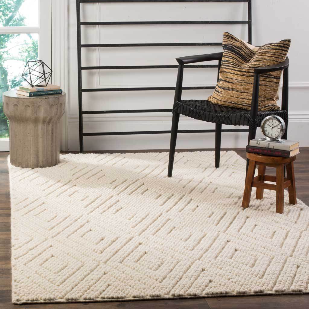 Soft ivory rug with textured diamond motifs adds warmth beneath a contemporary chair