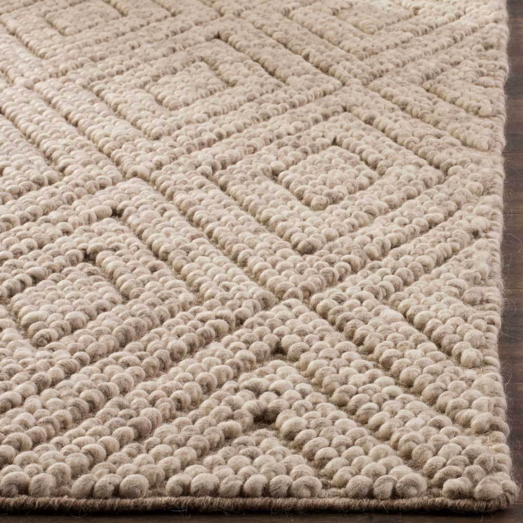 Plush beige wool loops trace nested diamonds along the rug's neatly finished edge